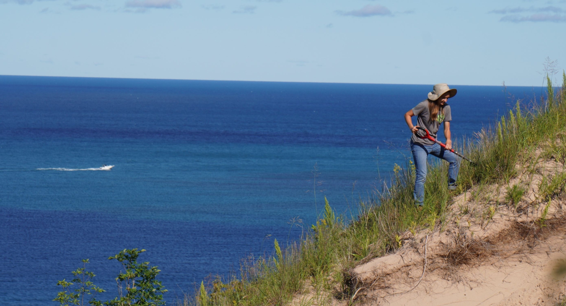 EcoCorps member holding a shovel and looking at a very green vista.